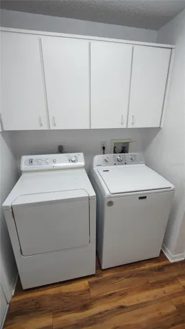 Laundry room has storage cabinets over the washer and dryer