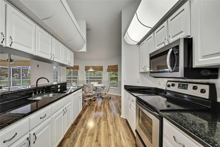 Kitchen looking toward kitchen nook. Long granite breakfast bar separates the kitchen and living room.