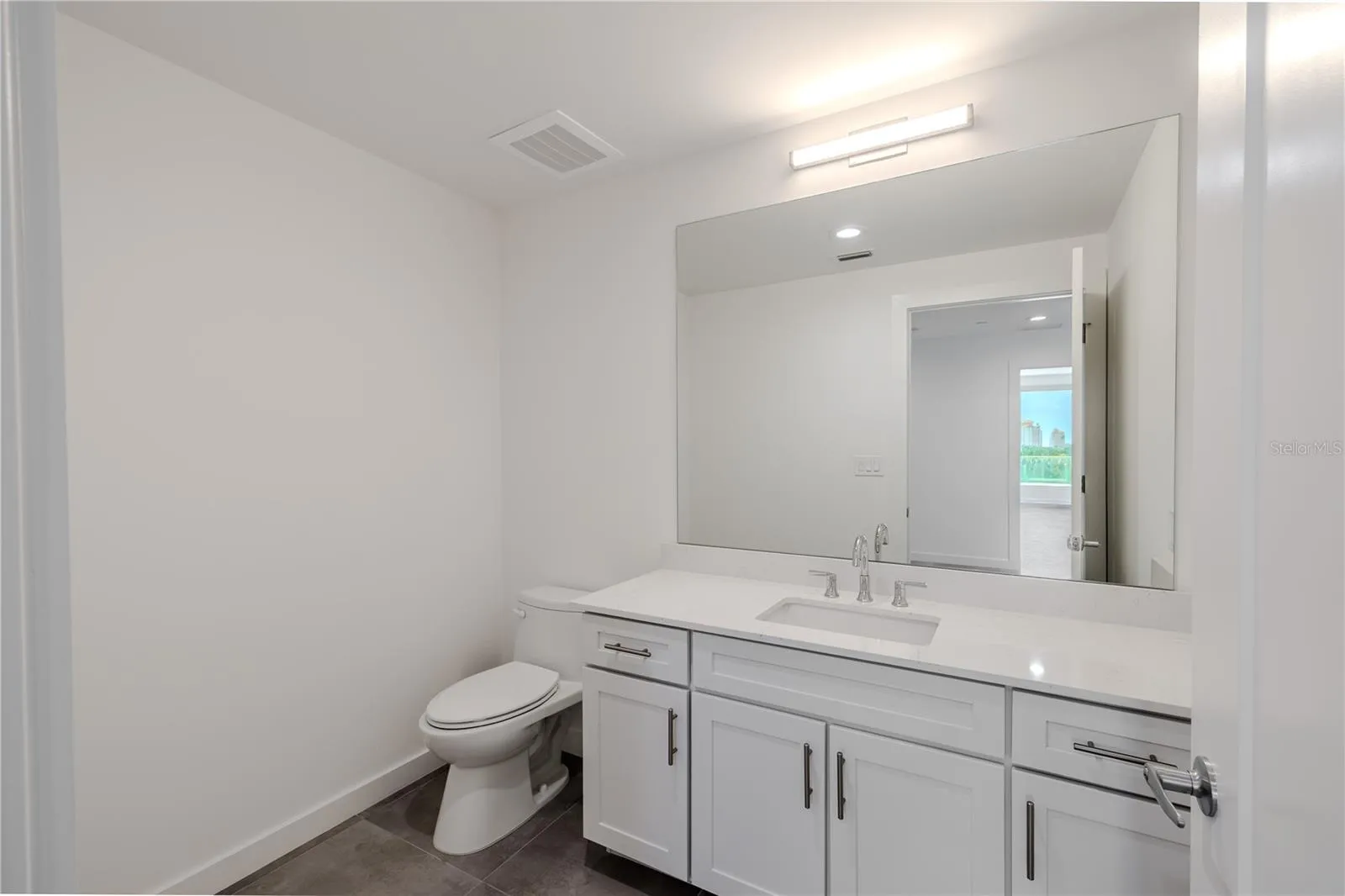 Guest bathroom #4 continues the home’s clean, modern aesthetic with a bright, streamlined design. The vanity features shaker-style cabinetry with brushed nickel hardware, a sleek quartz countertop, and an undermount sink complemented by polished chrome fixtures.A large, framed mirror and contemporary lighting create a well-lit, sophisticated atmosphere, while neutral tile flooring adds warmth and durability. Conveniently located near the main living areas and guest quarters, this bathroom offers both function and style — ideal for guests or everyday use.