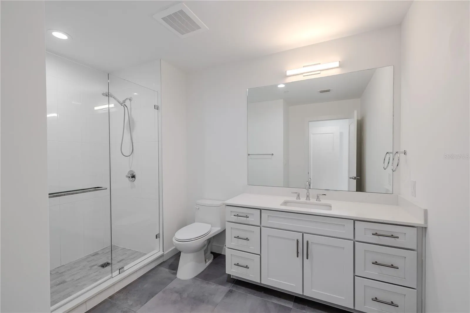 3rd bathroom Ensuite: The single vanity features shaker-style cabinetry with brushed nickel hardware, a sleek quartz countertop, and an oversized mirror with contemporary lighting above. Thoughtfully designed for both comfort and style, this ensuite combines modern elegance with everyday functionality — a private, polished extension of Bedroom 3.