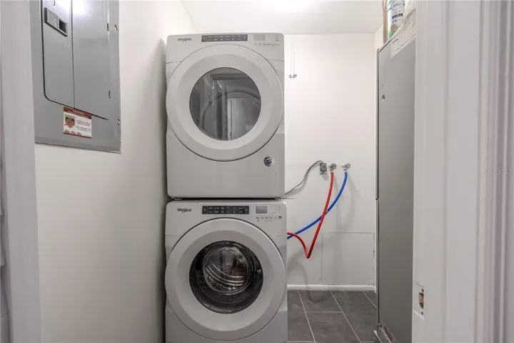 The laundry room offers a convenient and efficient setup with a modern Whirlpool washer and dryer stacked to maximize space. The area is well-lit and features easy-to-access water connections and tile flooring for durability and easy maintenance. Its practical layout provides functionality without sacrificing style, making laundry tasks simple and organized.