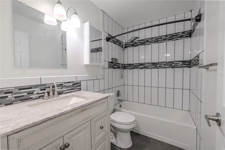 A classic vanity with a marble-look countertop provides both charm and functionality, complemented by brushed nickel fixtures and updated lighting.