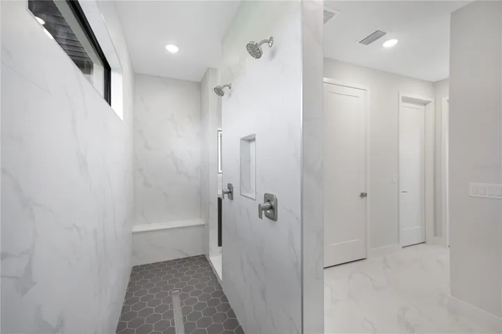 Primary shower with dual shower heads, built in storage, and benches
