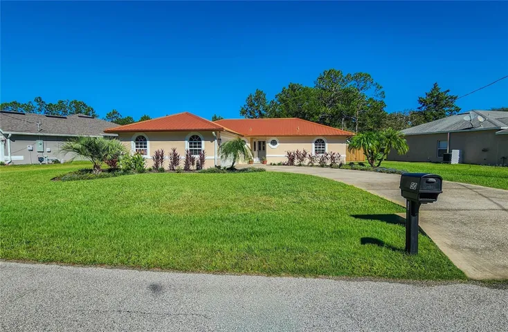 Curb appeal with updated landscape design, including decorative palms, low maintenance plantings and metal edging.