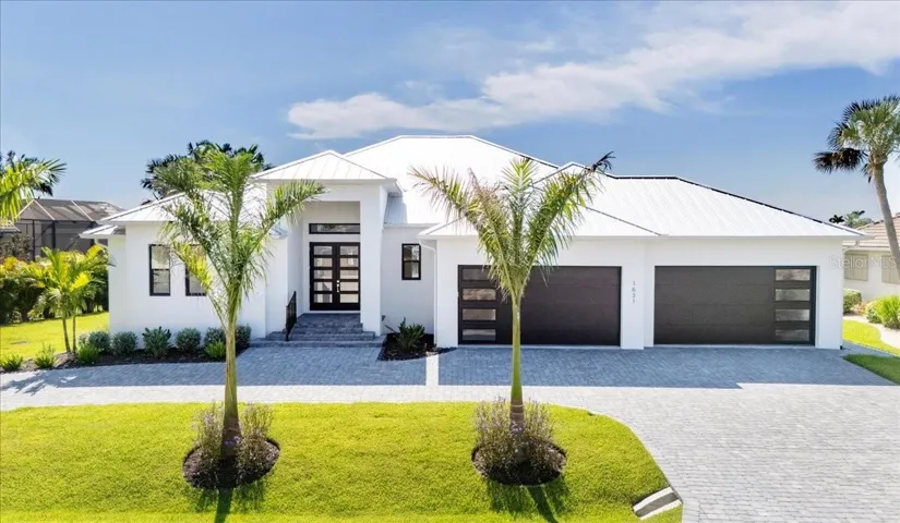 Elegant contemporary design with striking curb appeal, spacious four-car garage, an expansive circular paved driveway, and impressive double front doors