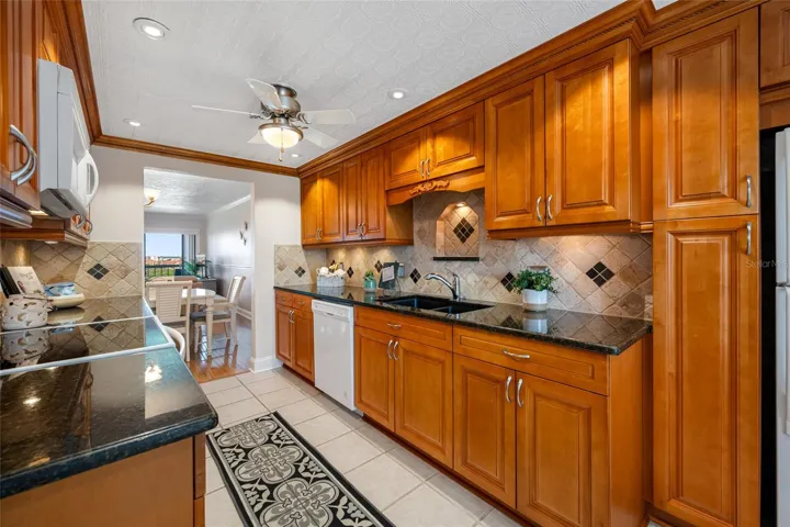 Kitchen with solid wood cabinetry, custom tile backsplash, granite countertops. Dishwasher