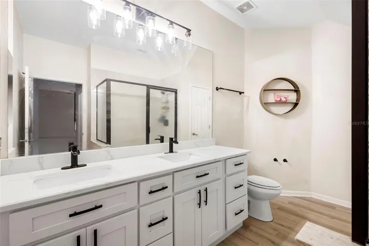 DOUBLE SINK, VANITY, STONE COUNTERTOPS AND WALKIN SHOWER.