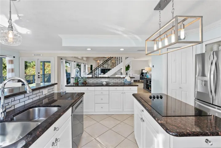 Chef’s kitchen with granite counters and stainless steel appliances upgraded lighting.