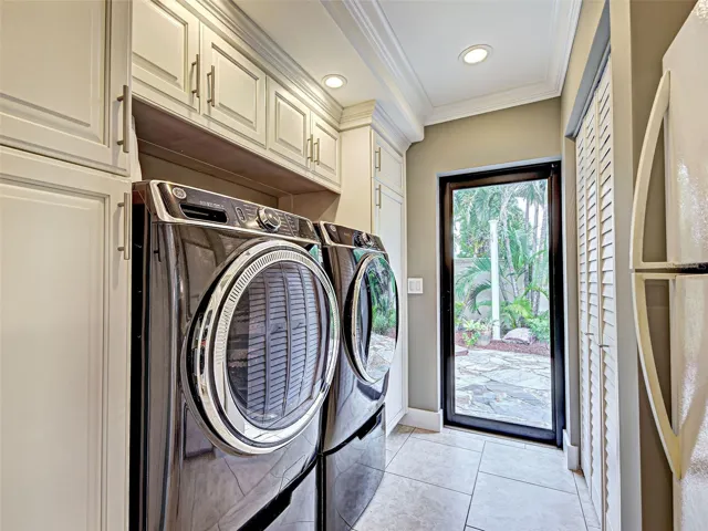 A well-appointed laundry room with cabinets and closets and a door to the outside.