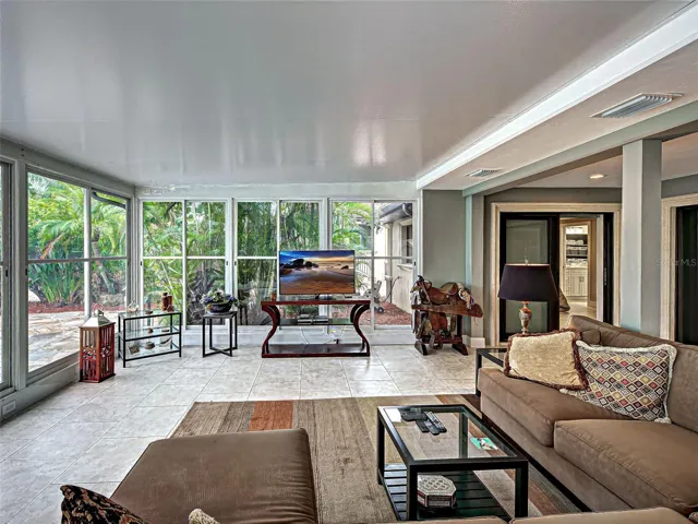 The air-conditioned lanai has walls of windows to enjoy the beautiful outdoor space with lush tropical landscaping and a view of the pool.