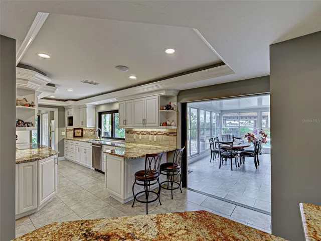 Seating for two at the breakfast bar, and the kitchen opens to the lanai with an informal dining area looking out at the pool.