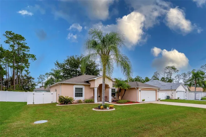 Beautifully maintained front yard with mature landscaping, a welcoming covered entry, and a stately palm tree centerpiece. The home features a two-car garage and a fully fenced backyard.