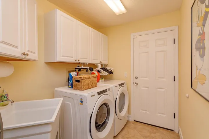 Laundry room has a soaking sink and cabinets for storage.