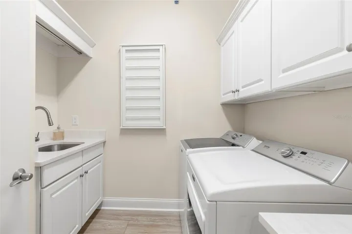 Oversized laundry room features extra storage, laundry sink, hanging space and counter space.