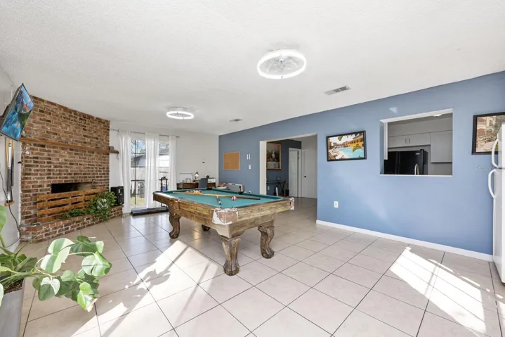 Versatile family room is complete with a brick fireplace and floor to ceiling windows.