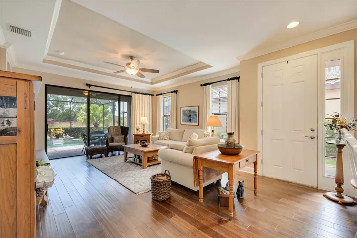 With light, space, and seamless flow, this Florida living room features sliding glass doors that open to the outdoors, an inset ceiling with crown moulding, and the perfect setup for indoor/outdoor living year-round.