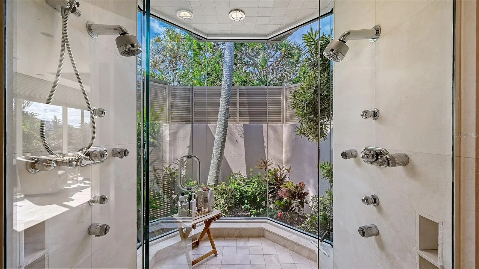 Glass-enclosed “outdoor” shower that offers breathtaking views of the outdoors featuring dual his-and-her shower heads, allowing both style and functionality