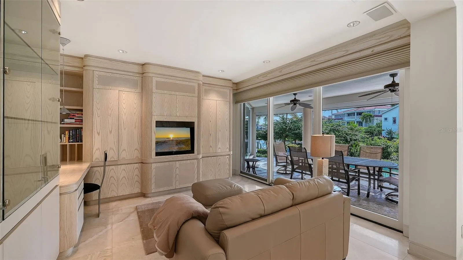 Primary bedroom lounge with extensive built-ins and sliding glass doors opening directly to the screened lanai, pool, and spa