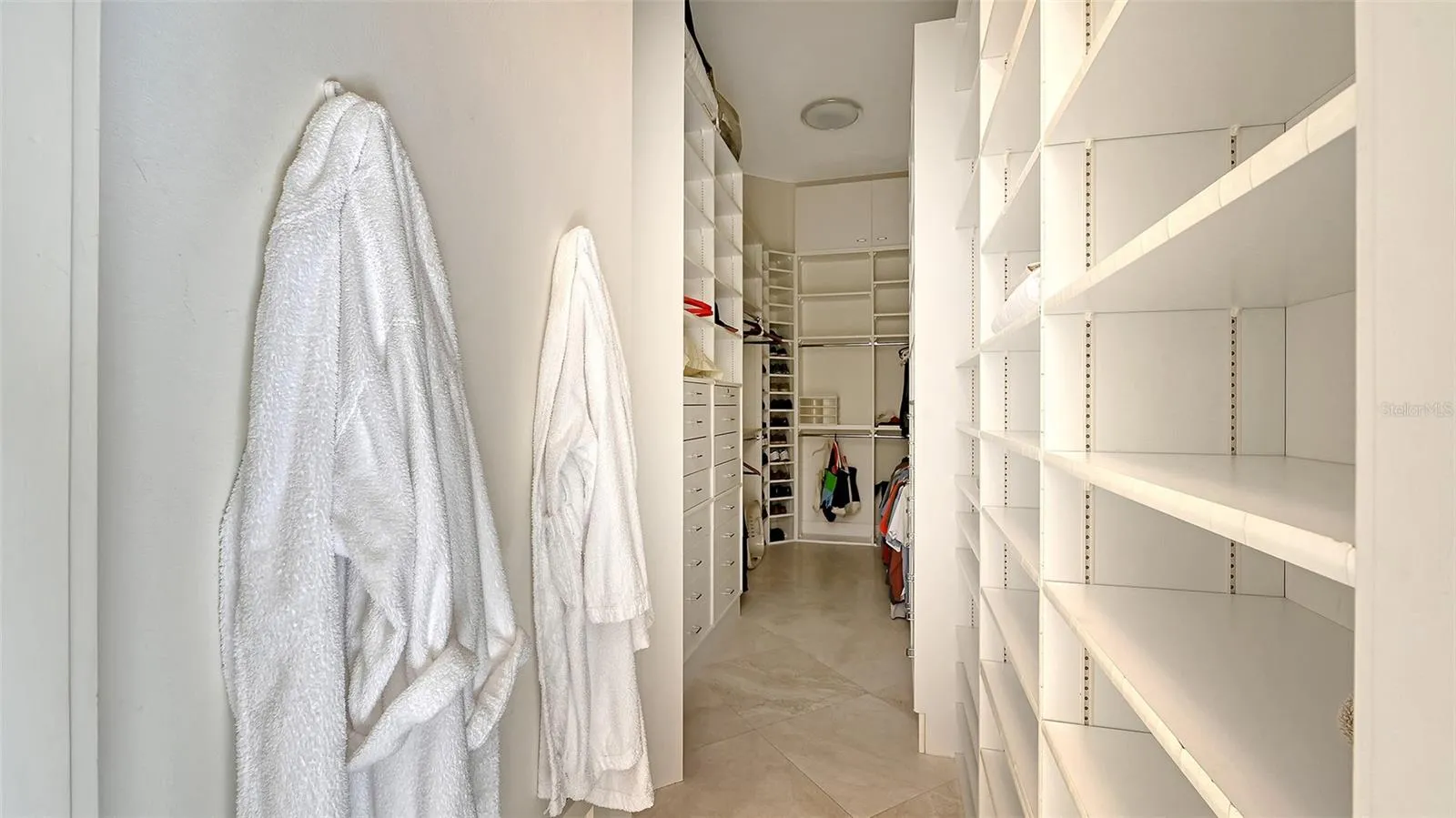 Spacious primary suite closet with custom built-in shelving for organization and style