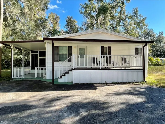 2004 Manufactured home with 1440 heated sf. Covered front porch and a covered patio leading to the screen room (vinyl sliding windows), and a door leading to the living space.