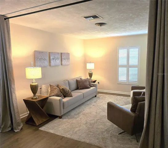 Living room has been utilized as additional guest space by adding a sleeper sofa and privacy drapes