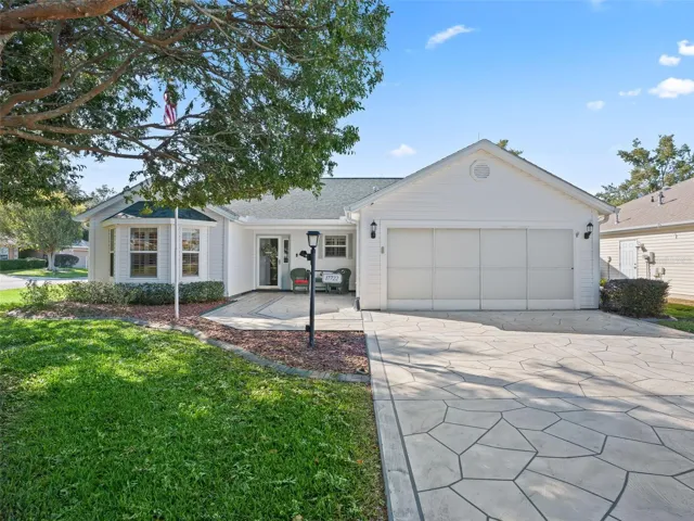 Driveway and Front Entry – Decorative stamped concrete driveway leads to a covered front porch with seating, offering both style and functionality.