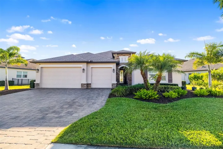 Captivating curb appeal in the heart of Greyhawk Landing with 3 an oversized 3 car garage, paver driveway, surrounded by lush tropical Florida palms.