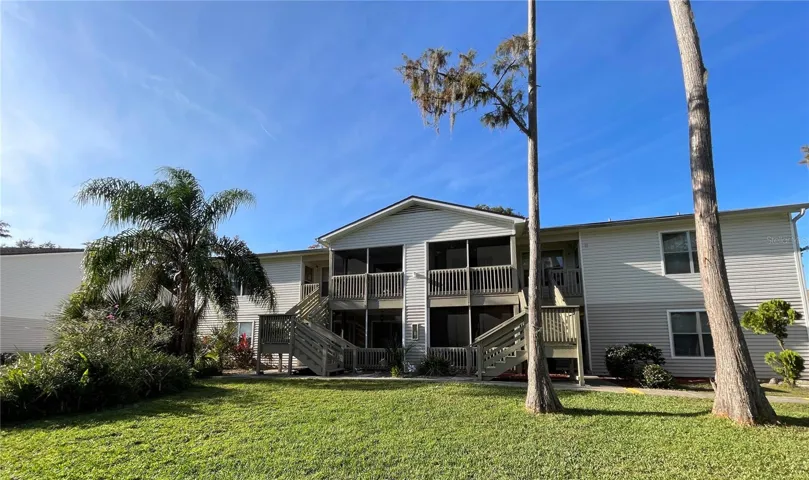 A view of the building shows well-maintained grounds, tropical landscaping, and easy access to the screened patio.