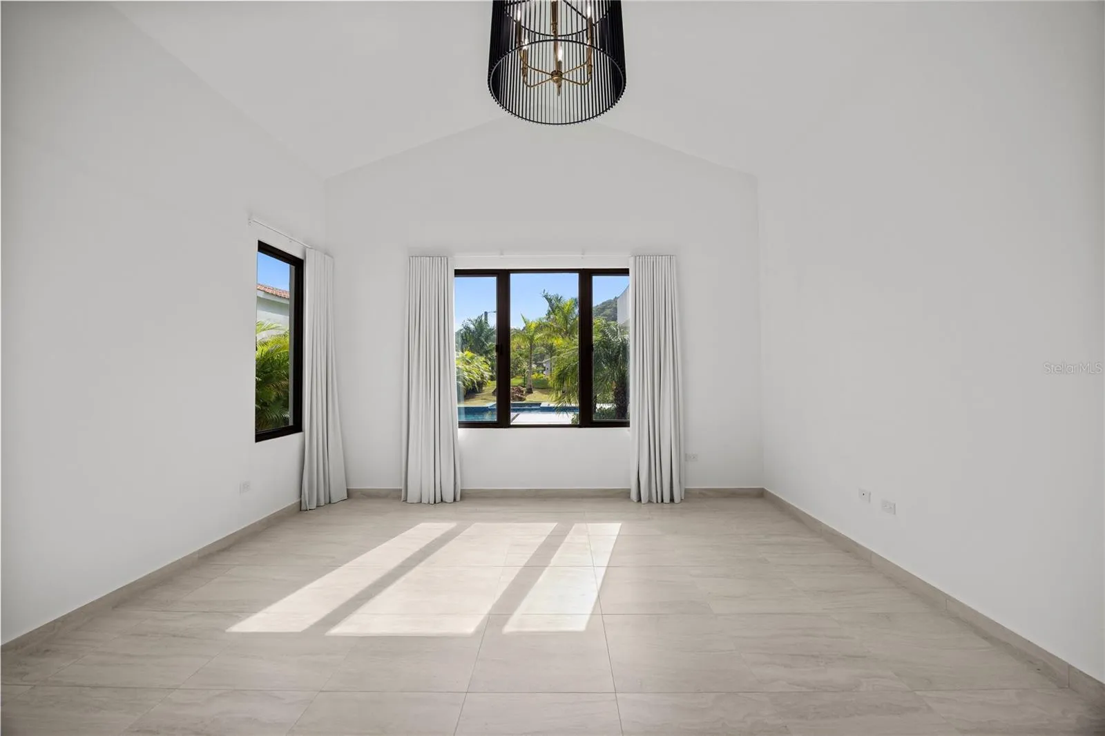 The primary suite includes an air-conditioned walk-in closet and a generously sized bathroom with double sinks, a double shower, and a separate toilet and bidet. High cathedral ceilings elevate the expansive living and dining areas, creating a bright and open atmosphere.