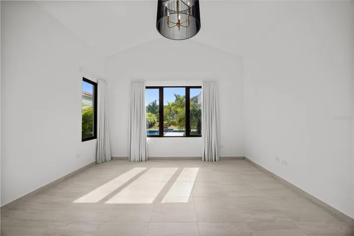 The primary suite includes an air-conditioned walk-in closet and a generously sized bathroom with double sinks, a double shower, and a separate toilet and bidet. High cathedral ceilings elevate the expansive living and dining areas, creating a bright and open atmosphere.