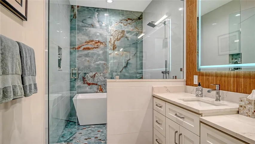 Luxurious primary bathroom offering dual vanities, a make-up station, a walk-in shower with soaking tub and Grohe chrome shower head and separate hand held sprayer.