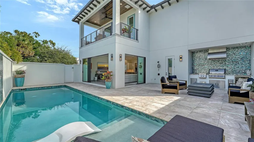 Pool deck and rear view of house and outdoor kitchen entertaining space.