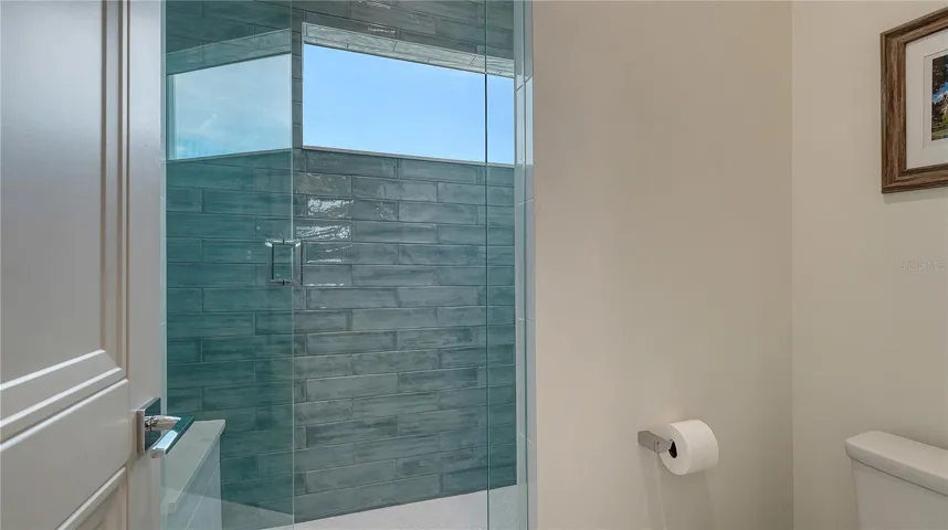 Jack and Jill bathroom with private toilet and walk-in shower with bench seating and window.