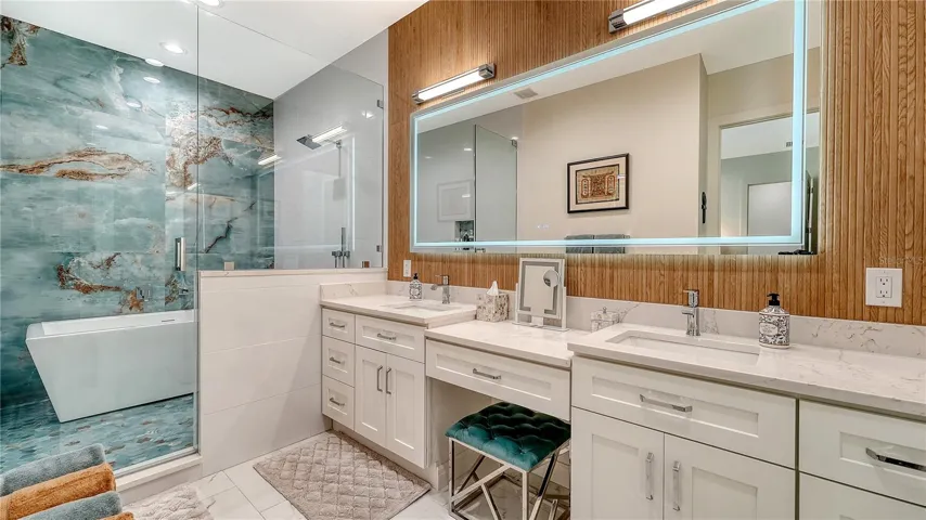 Luxurious primary bathroom offering dual vanities, a make-up station, a walk-in shower with tub and Grohe shower head and separate handheld sprayer.