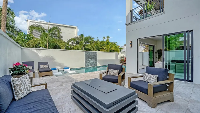 Outdoor conversation space with fire table beside the outdoor kitchen and pool deck.