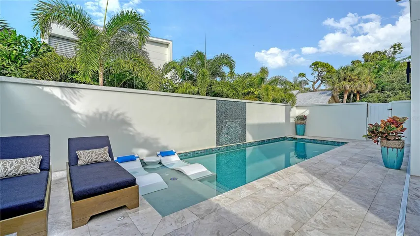 Marble pool deck with sun deck and fountains.