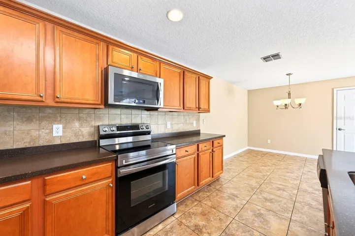 The Kitchen is designed to be the heart of the home, featuring STAINLESS STEEL APPLIANCES, a stylish tile backsplash, a closet pantry, abundant cabinetry and counter space, and a BREAKFAST BAR ideal for casual meals or catching up with family and friends.