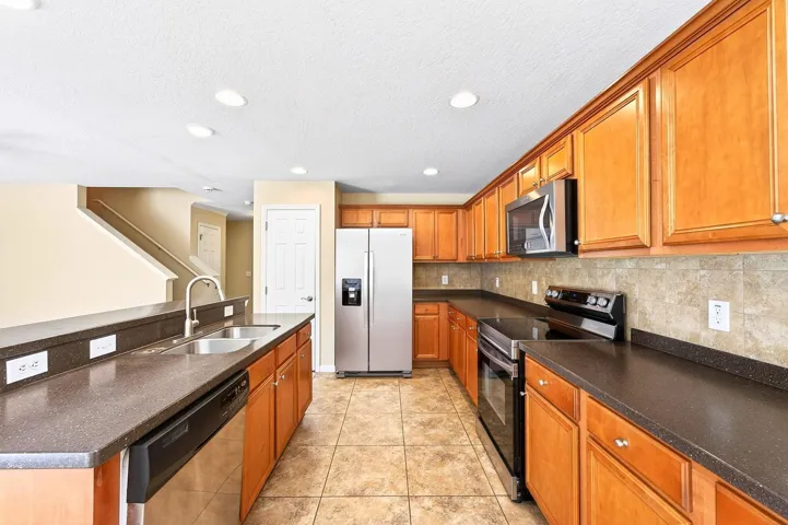 The Kitchen is designed to be the heart of the home, featuring STAINLESS STEEL APPLIANCES, a stylish tile backsplash, a closet pantry, abundant cabinetry and counter space, and a BREAKFAST BAR ideal for casual meals or catching up with family and friends.