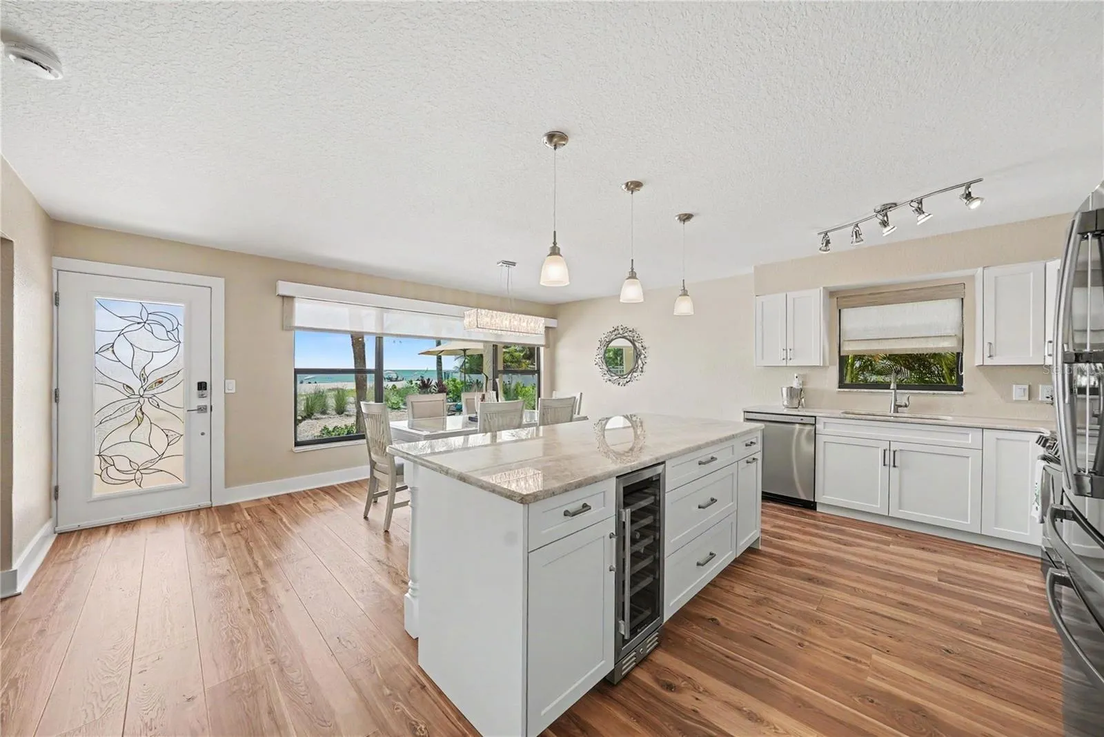 Quartzite counters, oversized kitchen island and space for a large dining room, new cabinets, appliances, 4" baseboards, paint, and flooring. Enjoy remote window shades with expansive views of the beach from both the living room and kitchen.  Bonus kitchen window allows for Florida breezes too!