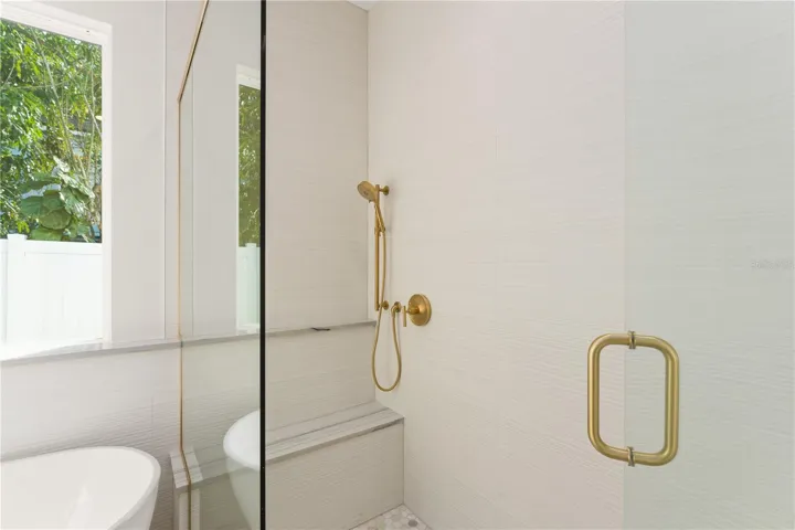Inside the large, walk-in primary shower there are double shower heads and a shower bench.