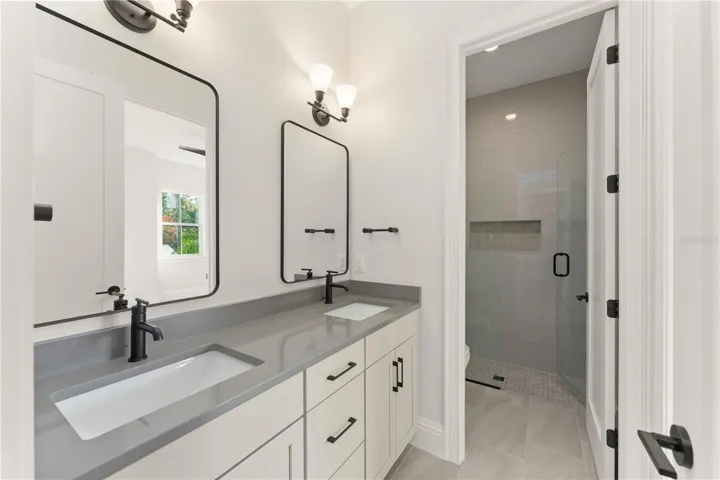 Bathroom 3 upstairs offers a private room with a commode and walk-in shower, with frameless shower enclosure, and a double vanity with drawers.