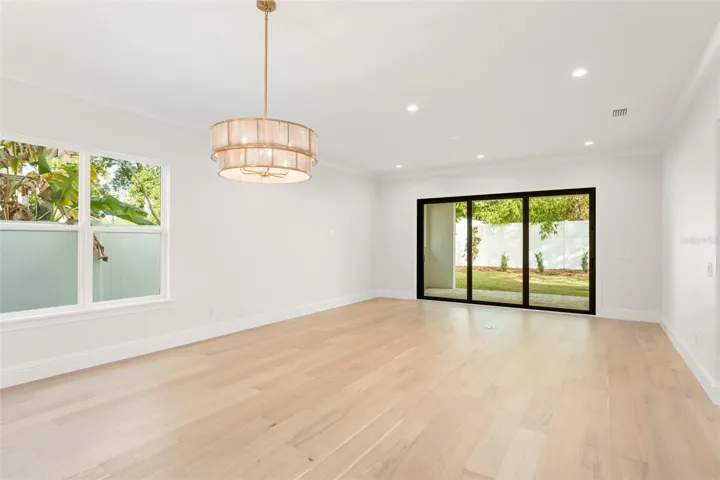 View of the dining room and living room, looking out through the large lanai to the backyard.