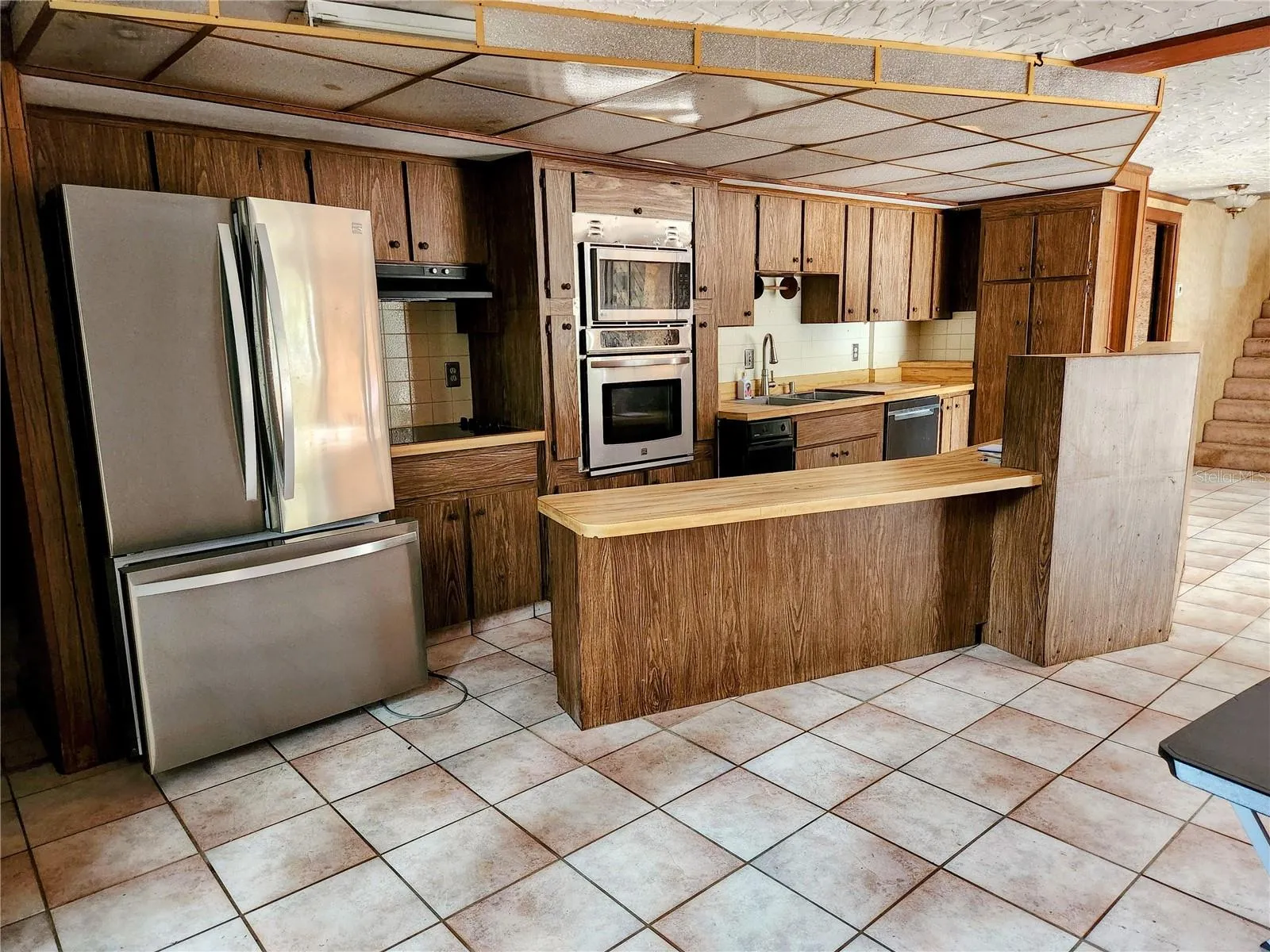Kitchen with new appliances.  There is a cooktop with range hood, a built in microwave and oven as well as a dishwasher