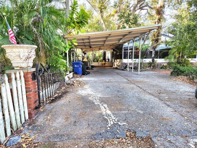 extra wide driveway accomodates many vehicles. Pool cage is to the right of carport.