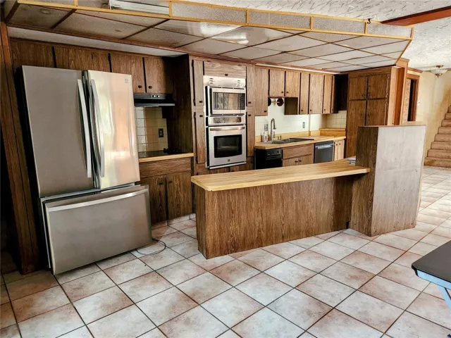 Kitchen with new appliances.  There is a cooktop with range hood, a built in microwave and oven as well as a dishwasher