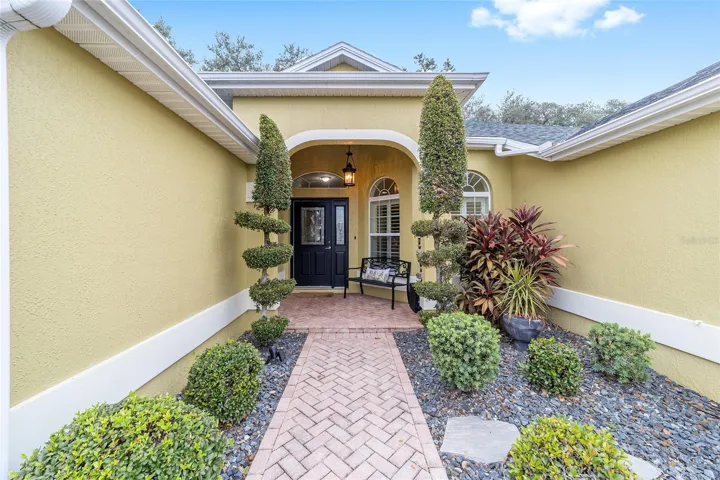Beautiful paver lined entry with landscaping topiary