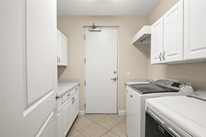 Large utility room with lots of storage, hanging space and utility sink.