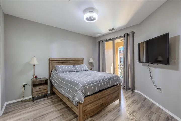 Primary bedroom retreat featuring sliding glass doors to the private balcony, soft neutral tones, modern lighting, and easy access to the main living area, creating a bright and comfortable space to unwind.