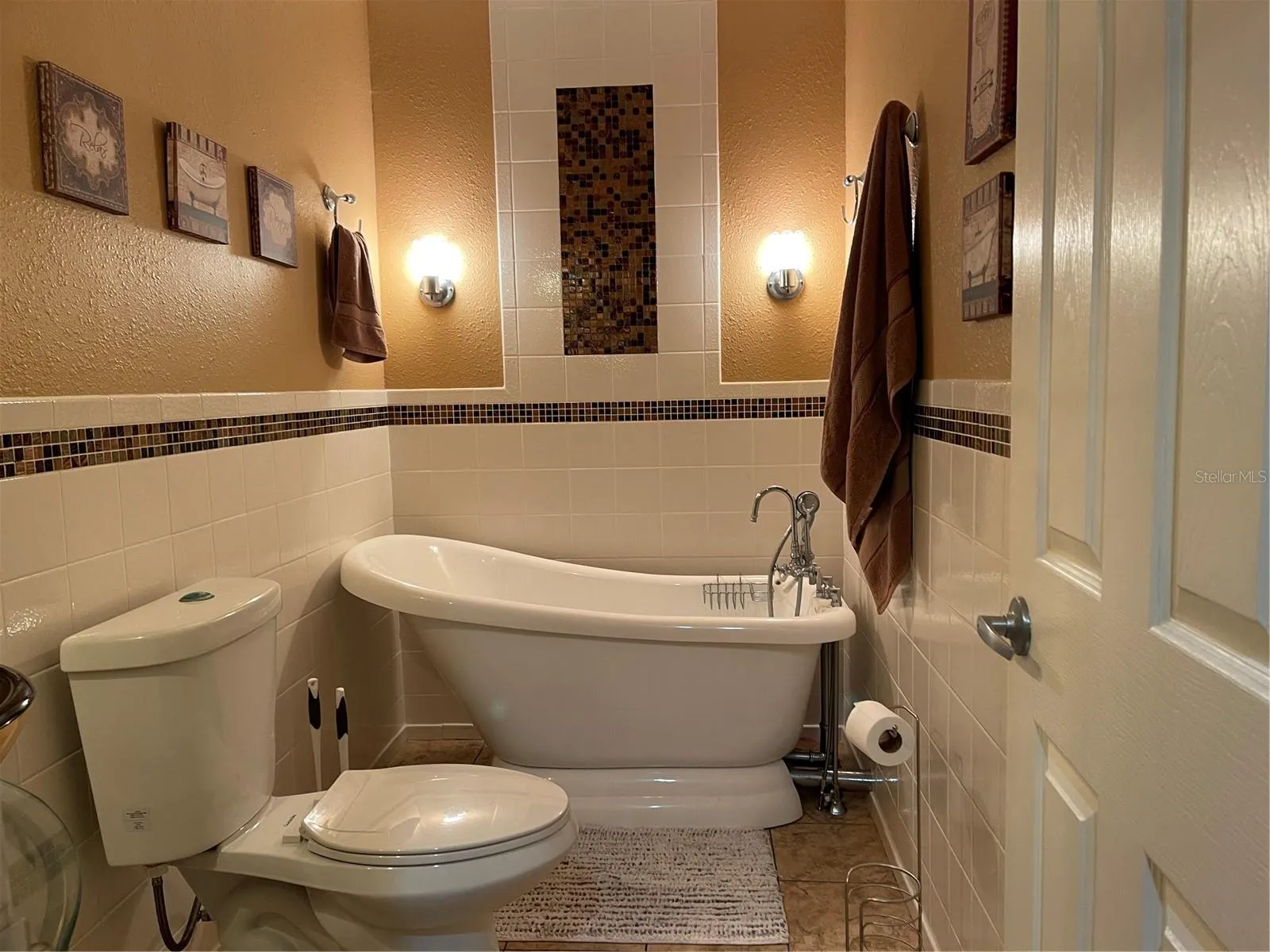 Soaking tub in guest bathroom has sconce lights above it.