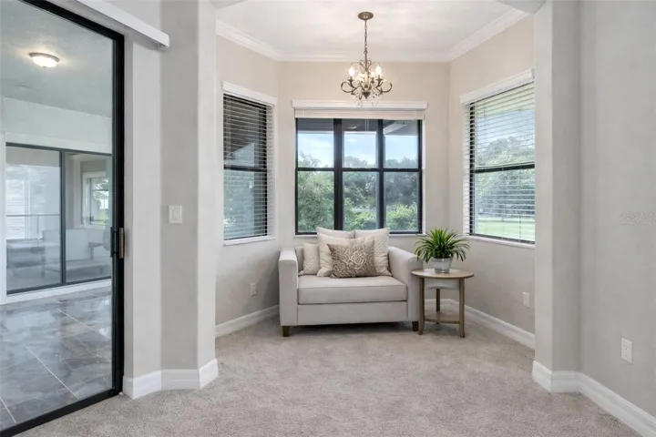 Cozy master-suite sitting nook with designer lighting—plus sliding doors just steps away that open to the expansive lanai for effortless indoor-outdoor living. Furniture virtually staged.